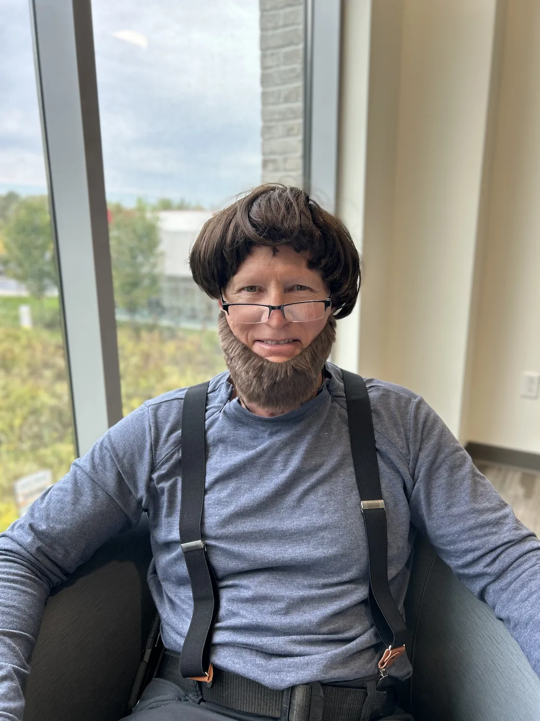 Brian in a brown bowl-cut wig, a bushy fake beard, glasses, and suspenders